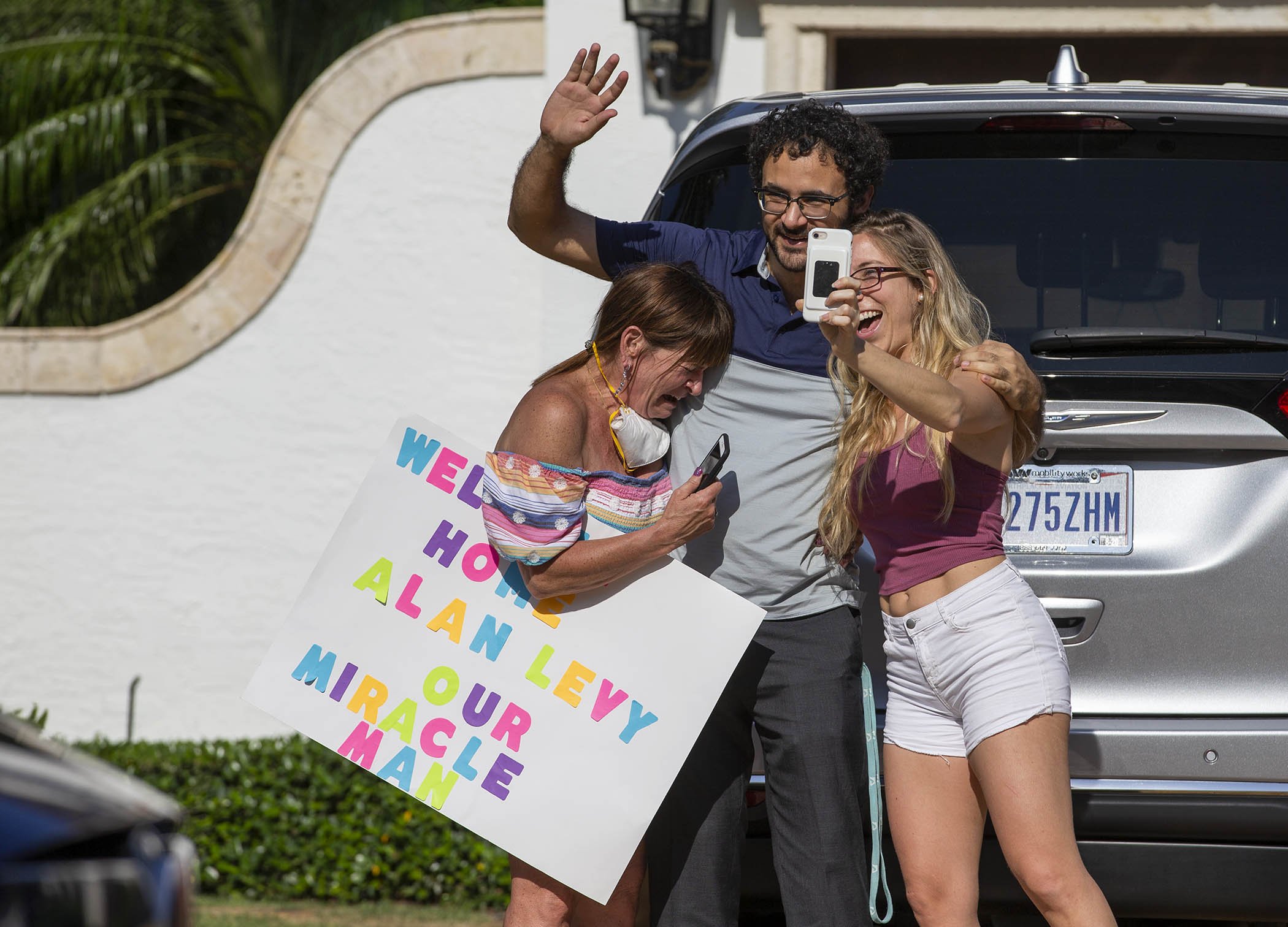 Andrea Wildman, left, Josh Levy and Carol Kaplan wave April 21, 2020, to neighbors and friends in Boca Raton welcoming home Josh’s father, Alan, after a near-death experience with COVID-19. Josh and his father could not get tests from health departments in early March when they felt they had coronavirus.