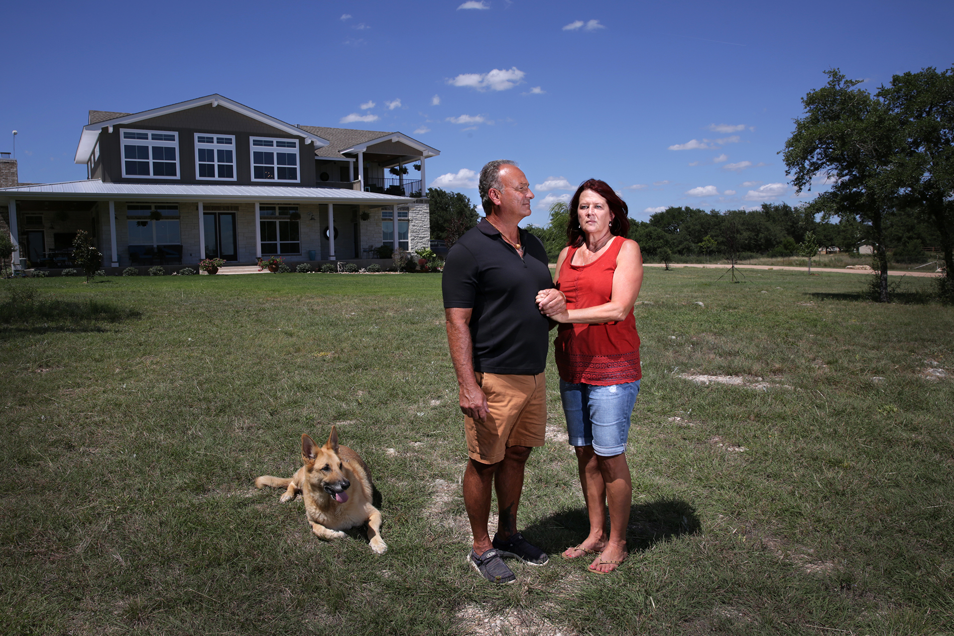 Retired Austin assistant fire chief, Kevin Baum, 57, stands with his wife Gwen, 56, and his dog Bonnie outside their home between Marble Falls and Burnet.