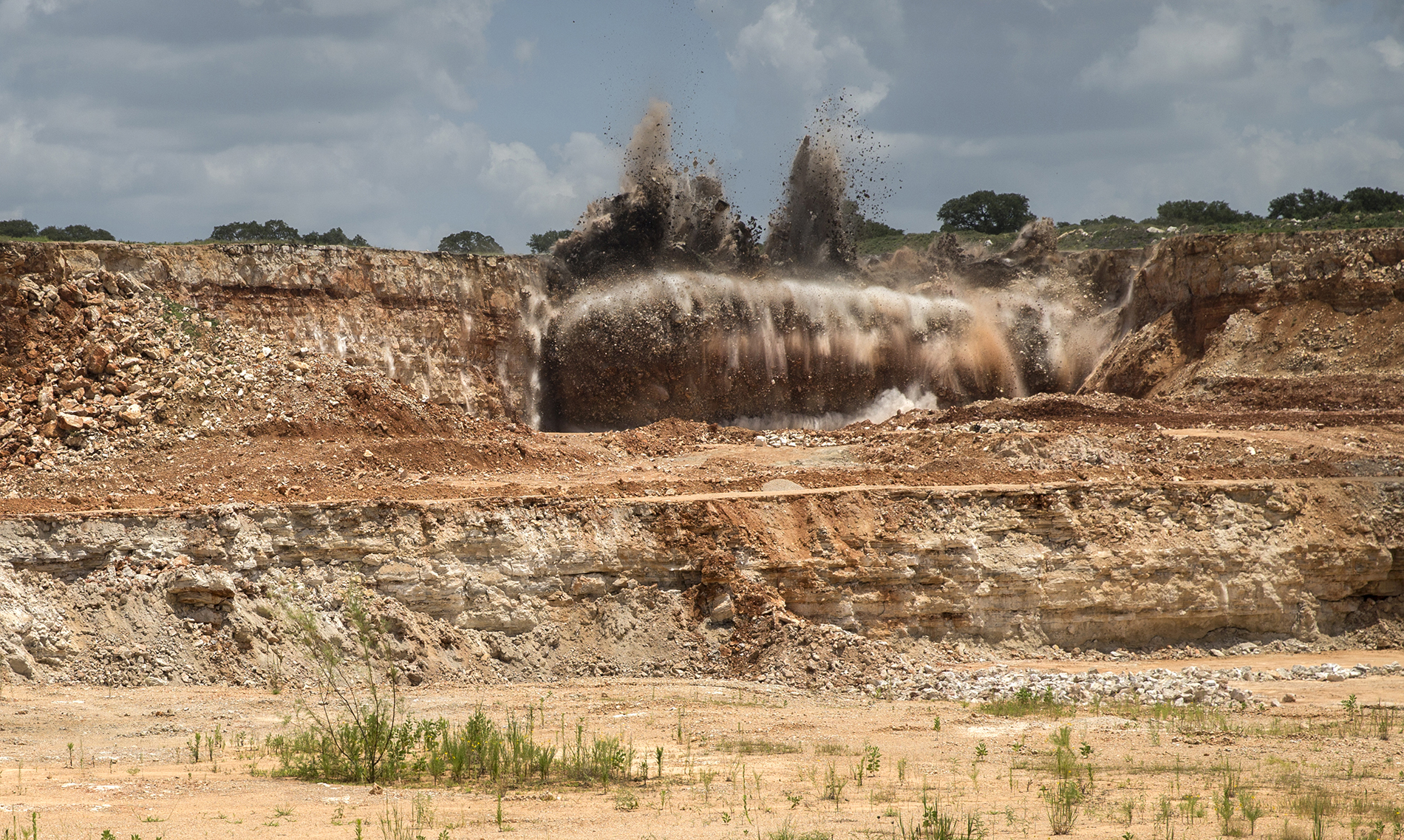 A blast sends chunks of limestone into the air in a mining pit at a quarry in Buda.