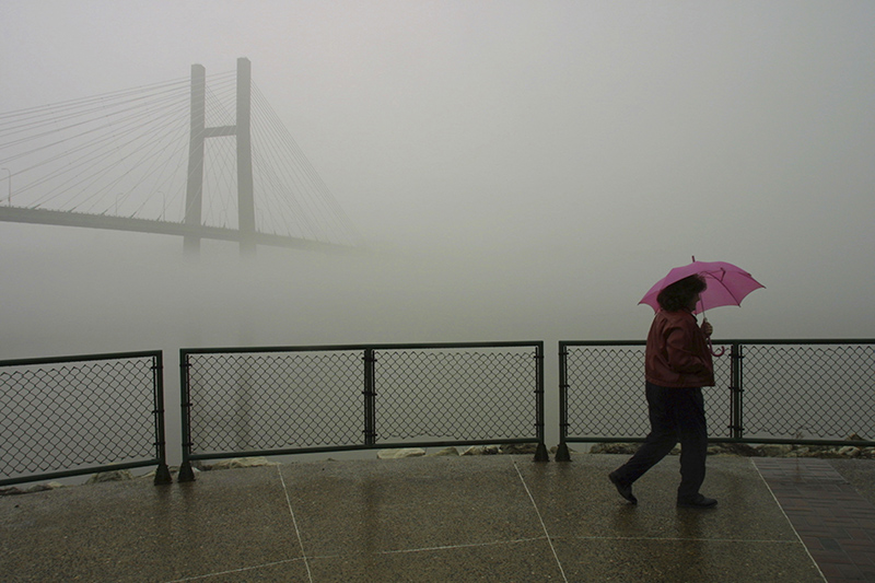 Maryellen Hitz of Kahiokia, Missouri, walks the riverfront in the drizzle and fog which covers the Great River Bridge April 6, 2001 in Burlington. | John Gaines | The Hawk Eye