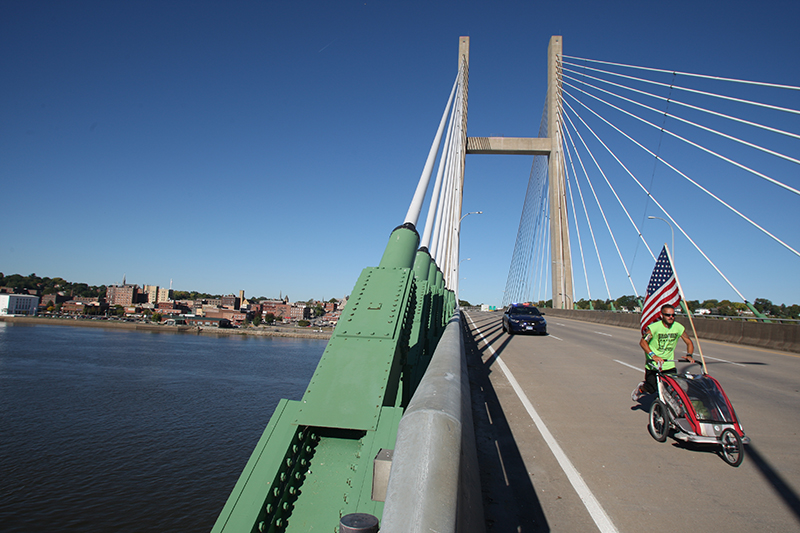 Noah Coughlan runs across the Great River Bridge on his second run across American bringing awareness to Batten Disease Oct. 8, 2013 over the Mississippi River heading east from Burlington. He said he'll go through 12 pairs of shoes on the run. | John Gaines | The Hawk Eye